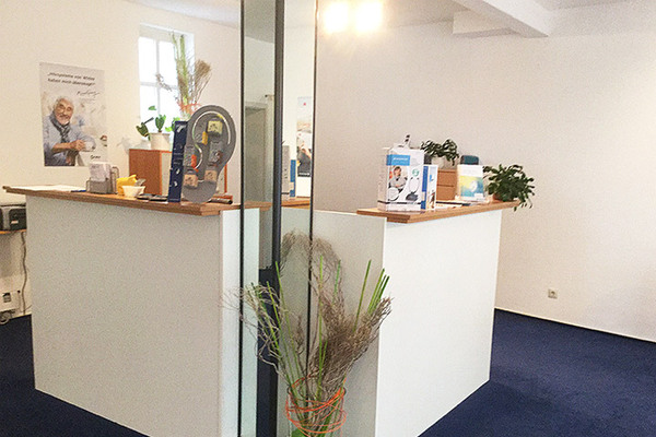 Heller Empfangsbereich mit Beratungstresen, Infomaterial und Pflanzen in einer Arztpraxis.